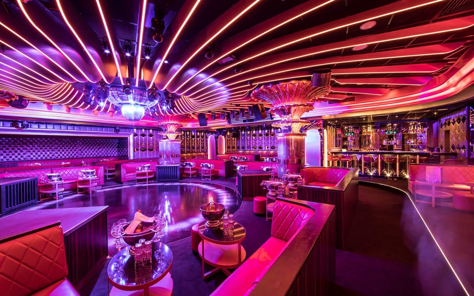 The Caves du Roy room in Saint-Tropez · red banquettes, bar and mirror ball beneath the glowing ceiling